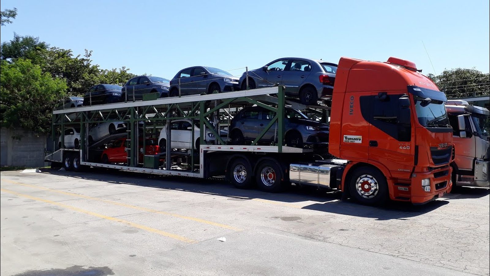Caminhão cegonha moderno carregado com automóveis em pátio de distribuição