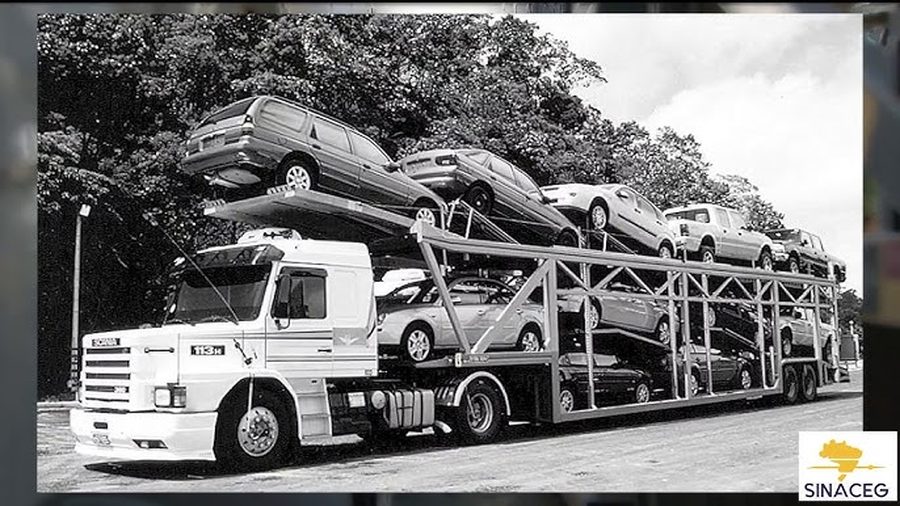 Caminhão cegonha antigo carregado de automóveis, em fotografia preto e branco